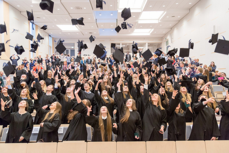 Studenci świętujący w auli ukończenie studiów/Students celebrating their graduation in the auditorium